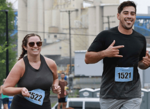 Two runners smiling and posing during a race, wearing bib numbers 522 and 1521, with a crowd in the background.